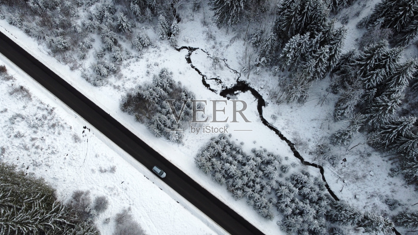 无人机拍摄的一辆汽车在冬天穿过森林的道路照片摄影图片