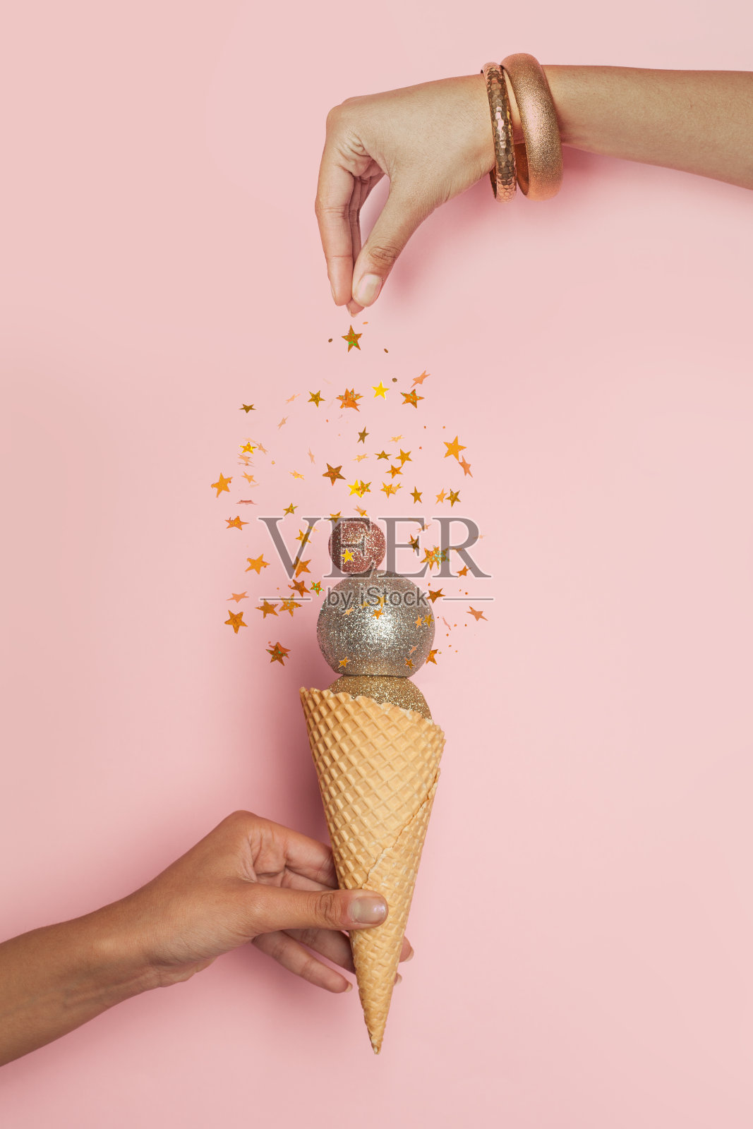 圣诞贺卡与飘落的五彩纸屑星星和球装饰在女性的手在粉红色的背景照片摄影图片