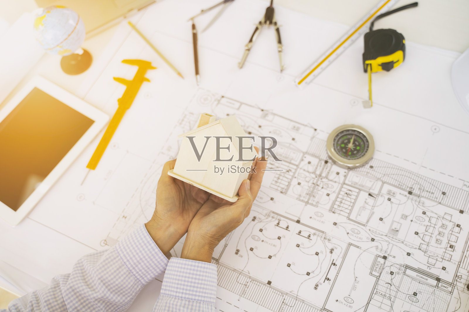 工程女孩拿着一个木屋建筑蓝图模型工程设备在我的桌子上。照片摄影图片