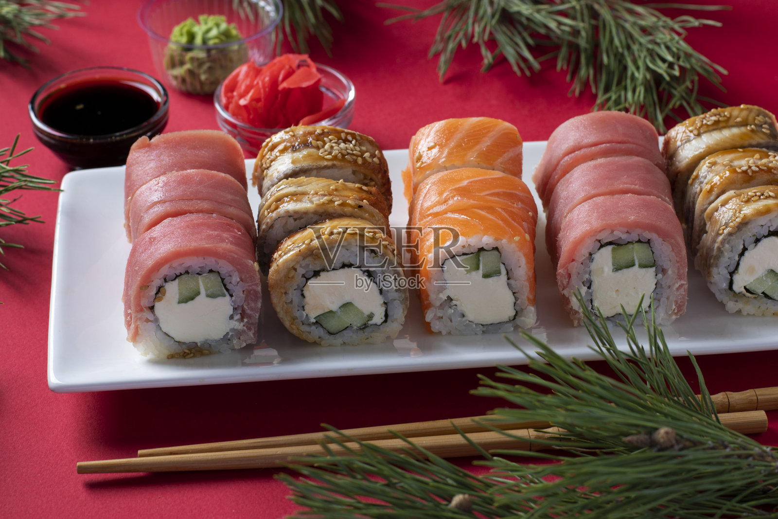 红底白盘,三文鱼、金枪鱼、鳗鱼寿司配费城芝士。新年聚会。照片摄影图片