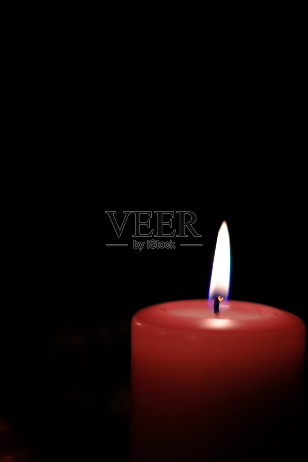 一个燃烧的红色蜡烛的特写和背景是黑暗的照片摄影图片