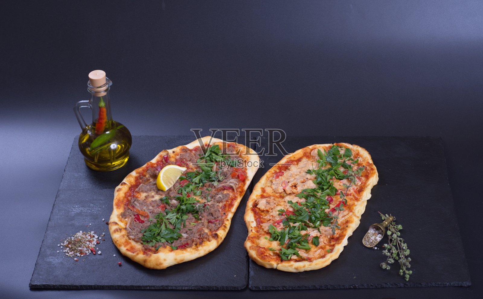 黑色的石头桌子上放着一个漂亮的披萨,上面有西红柿、肉和奶酪照片摄影图片