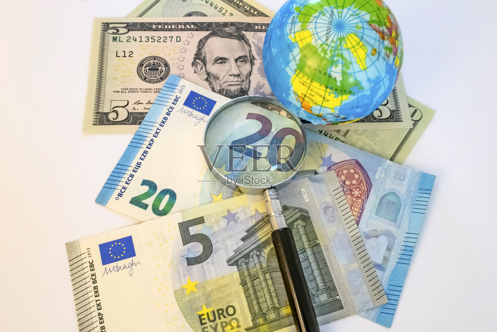 接近欧元和美元纸币与微型地球和放大镜在白色背景照片摄影图片