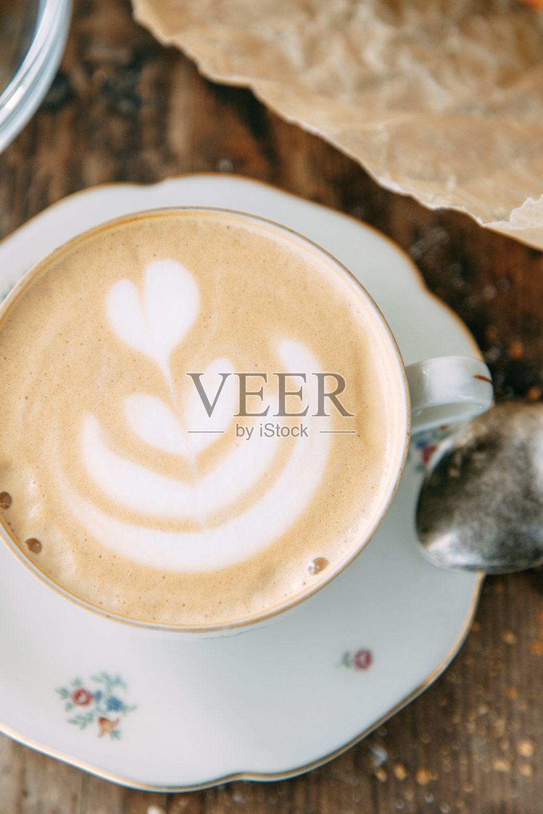 木桌子上放着卡布奇诺咖啡和一条面包。早餐,一个黄油面包和一杯咖啡。照片摄影图片