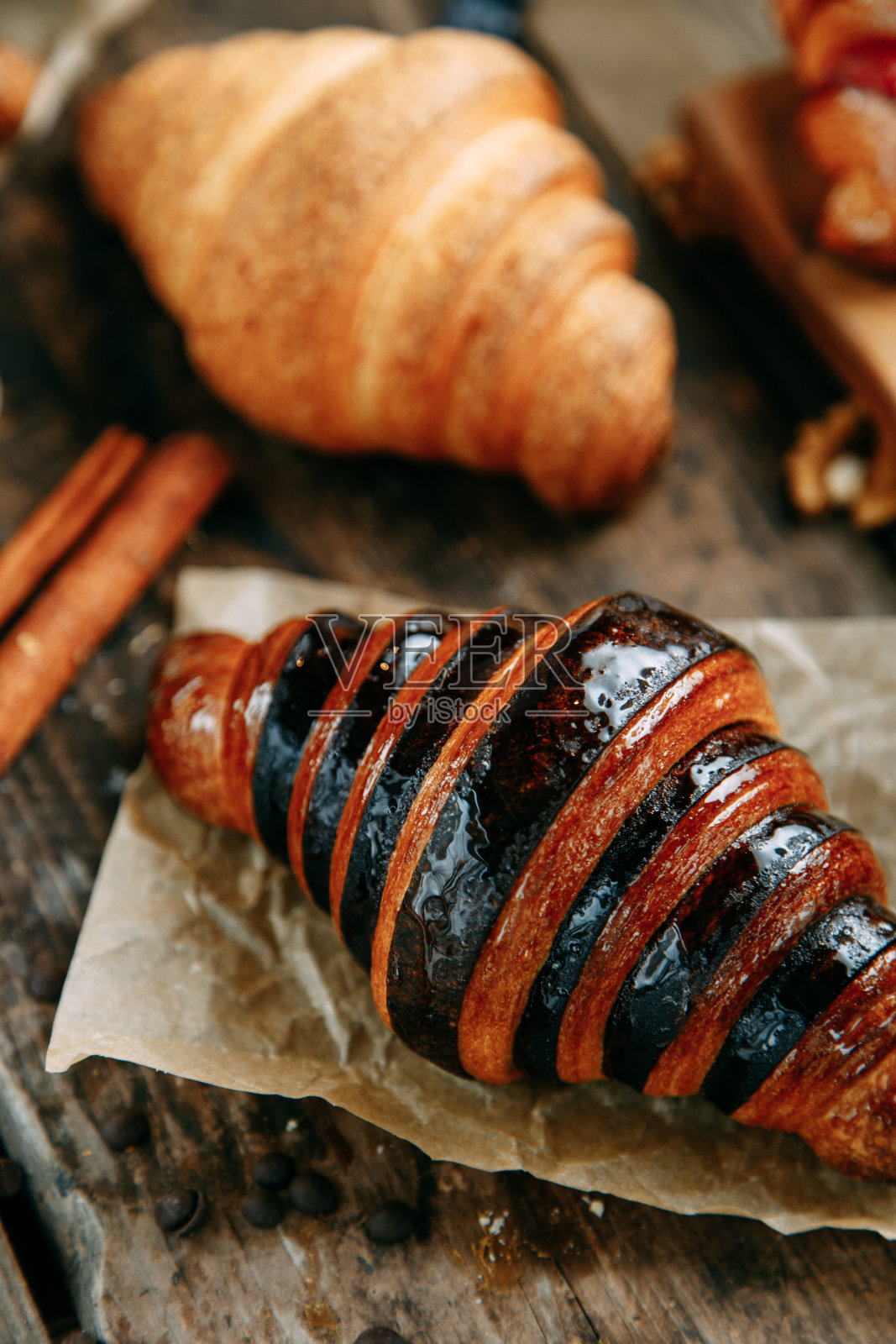 木桌上放着刚烤好的牛角面包。浆果和巧克力羊角面包在一个平面布局的特写。照片摄影图片