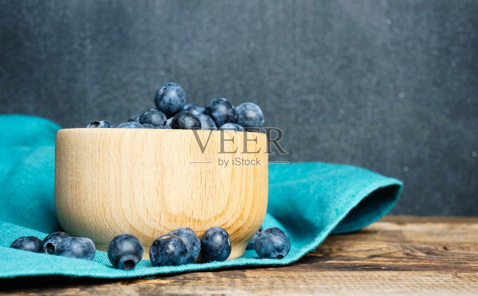 新鲜的蓝莓放在一个木碗里放在一个古老的木桌上,这是一种健康的食品理念照片摄影图片