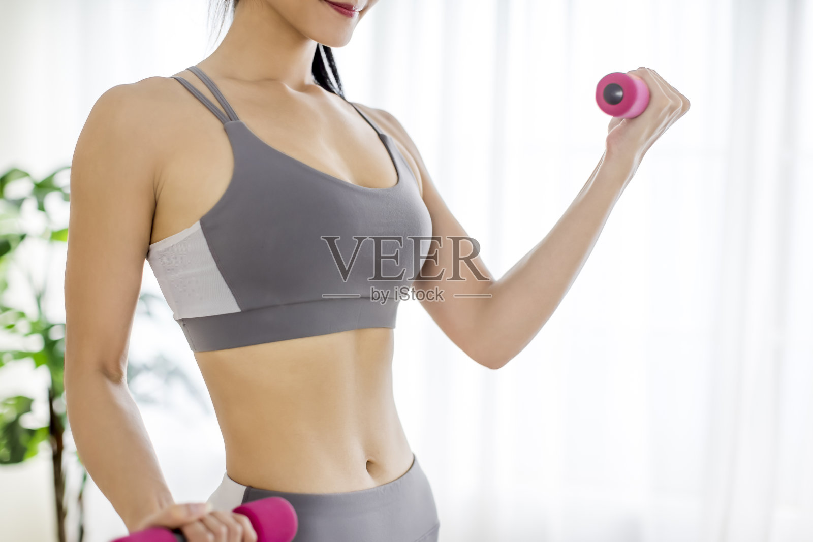 年轻女子在运动服装做健身操哑铃和显示腹肌照片摄影图片