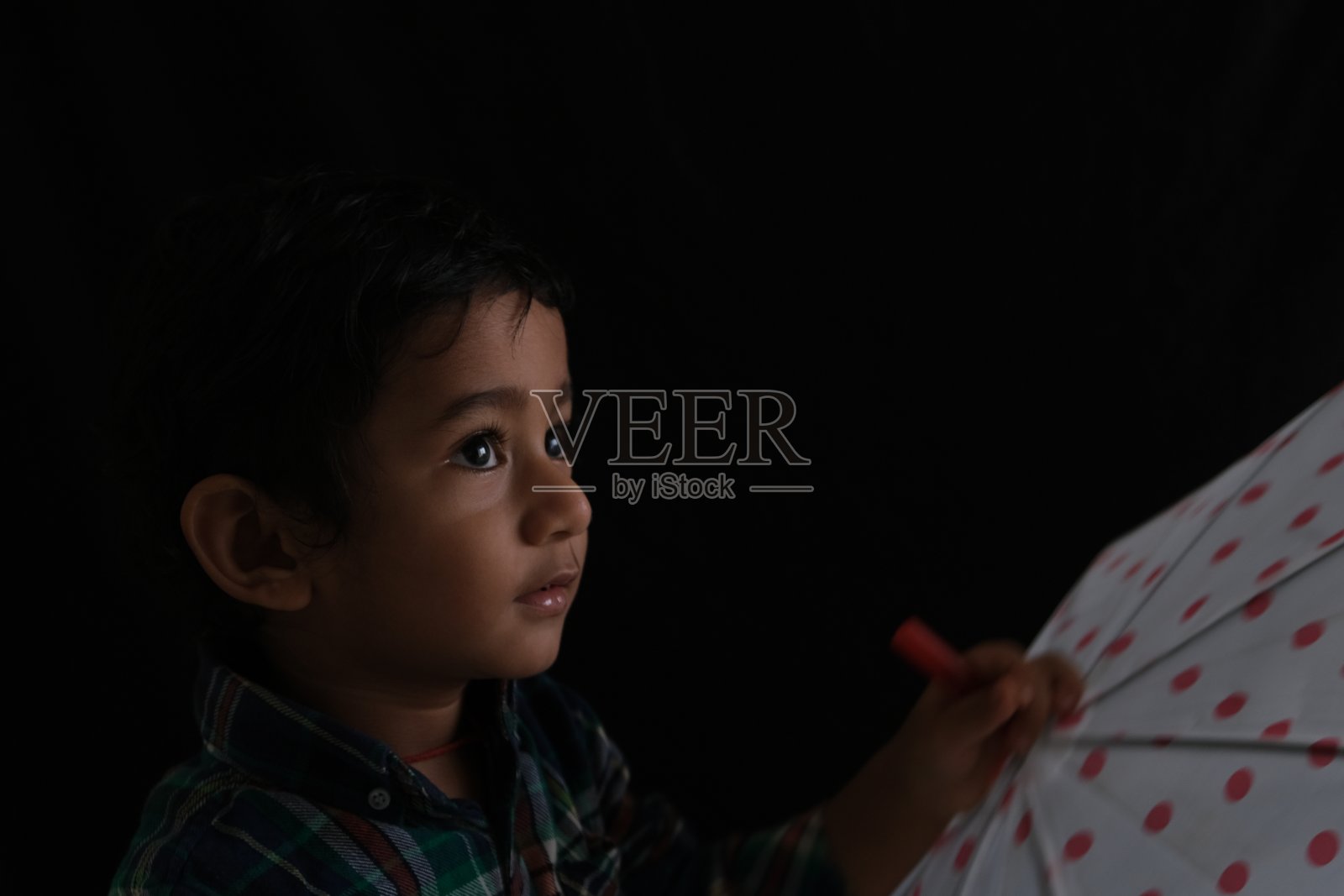 近距离的印度可爱的小可爱可爱的深色头发的泰米尔婴儿男孩穿着休闲连衣裙,在一个黑色的背景伞。照片摄影图片