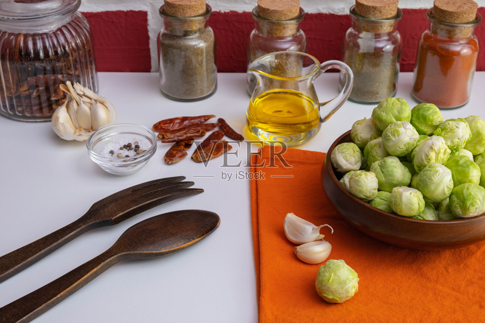 各种香料,大蒜,油,木制餐具,抱子甘蓝,桌布放在木碗里,砖红色背景照片摄影图片