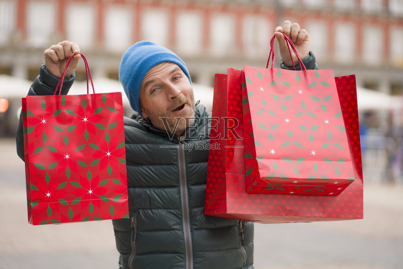 圣诞购物在城镇-城市生活方式肖像快乐和兴奋的男人在冬季帽子携带购物袋在圣诞市场微笑愉快和兴奋购买礼物照片摄影图片