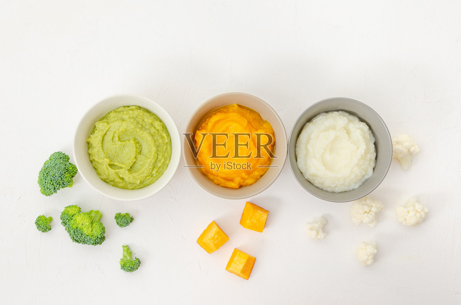 婴儿食品。变异的三碗自制蔬菜泥。南瓜泥,花椰菜泥和西兰花泥在白色的背景。前视图。照片摄影图片