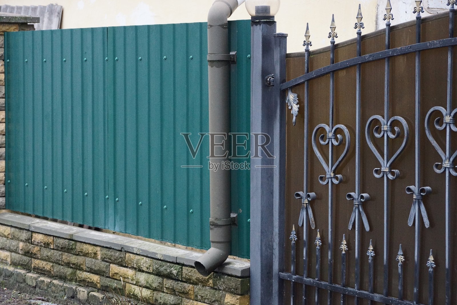 绿色墙边有长长的灰色金属排水管照片摄影图片