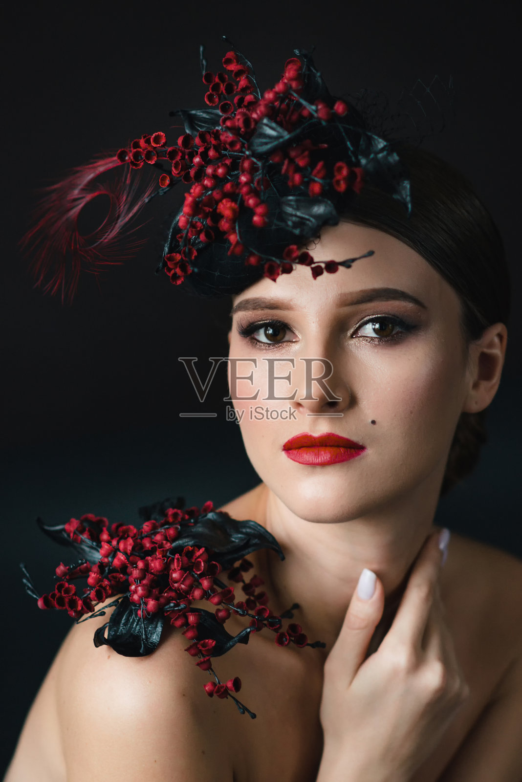 头发上插着花的漂亮女人。美丽肖像时尚模特与创意化妆和发型与红黑花照片摄影图片