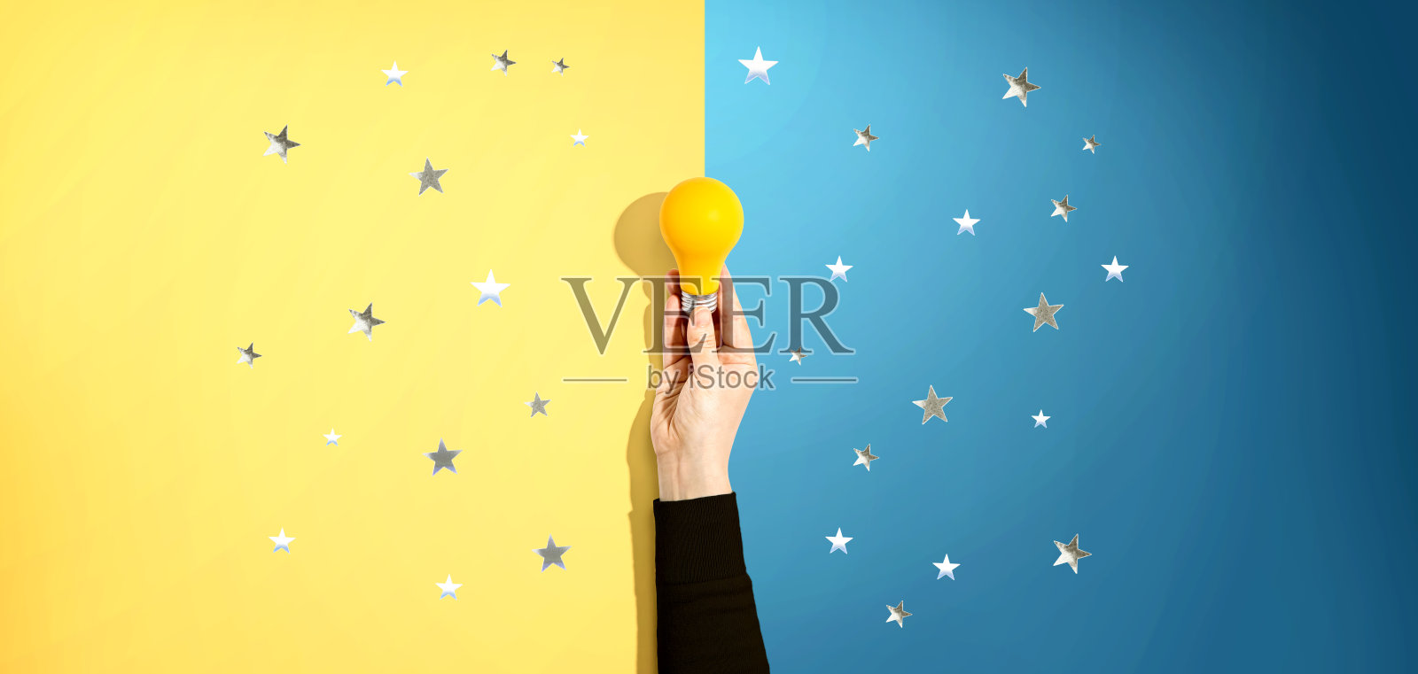 一个人拿着一个带星星的黄色灯泡照片摄影图片