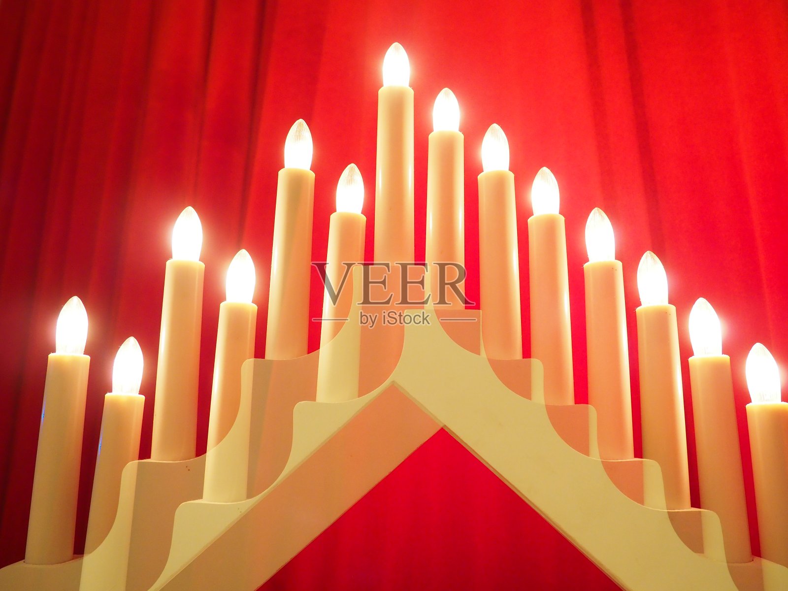 施威伯根拱形灯具,三角形烛台的形式。红色的背景。夜晚,浪漫、喜庆、宗教或神秘的气氛。燃烧的灯泡或烛光。双重曝光照片摄影图片