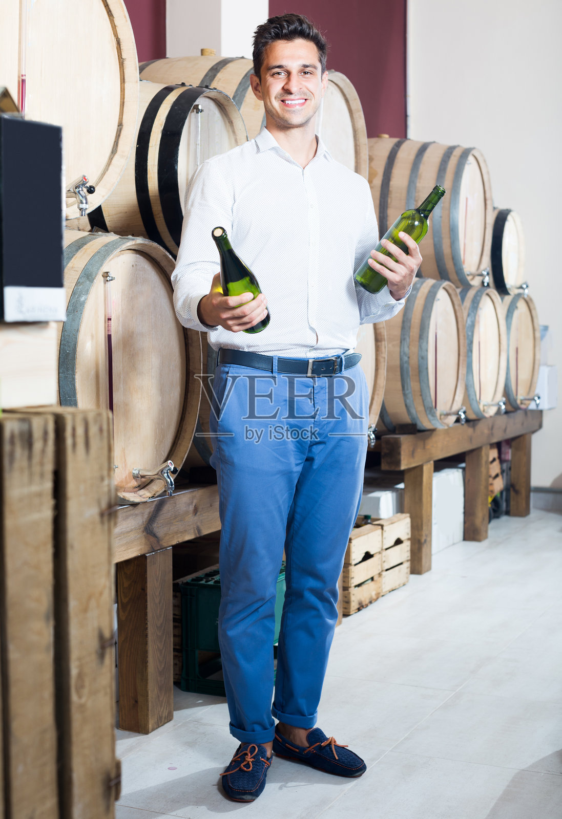 一个男人在酒窖里拿着一瓶酒照片摄影图片