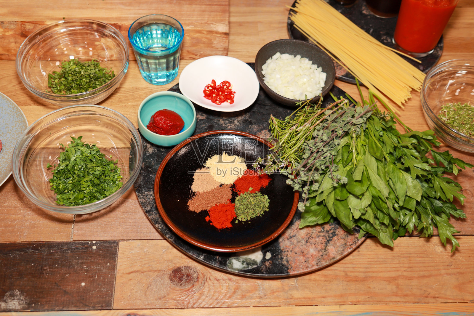 厨房木质台面上展示了香料、香草、香菜、洋葱和干意大利面,以及食物准备概念照片摄影图片