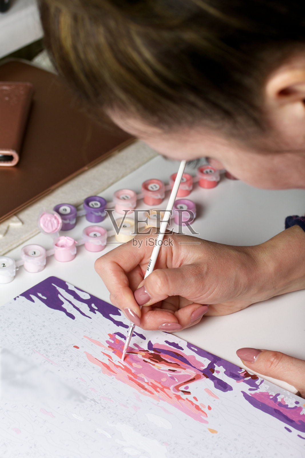 这个女人用数字作画。画布上的丙烯颜料。附近是油漆罐和其他配件。照片摄影图片