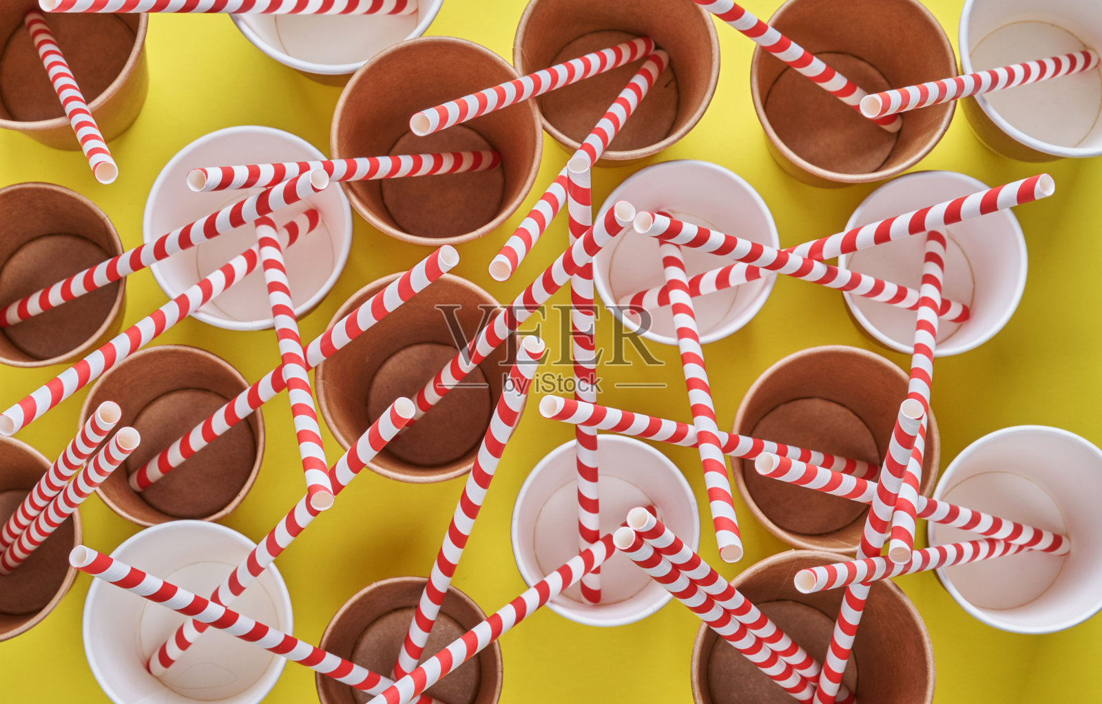 用红色的纸和玉米淀粉制成的吸管,在时髦的黄色背景的空纸杯里喝咖啡。零废物和无塑料的概念。照片摄影图片