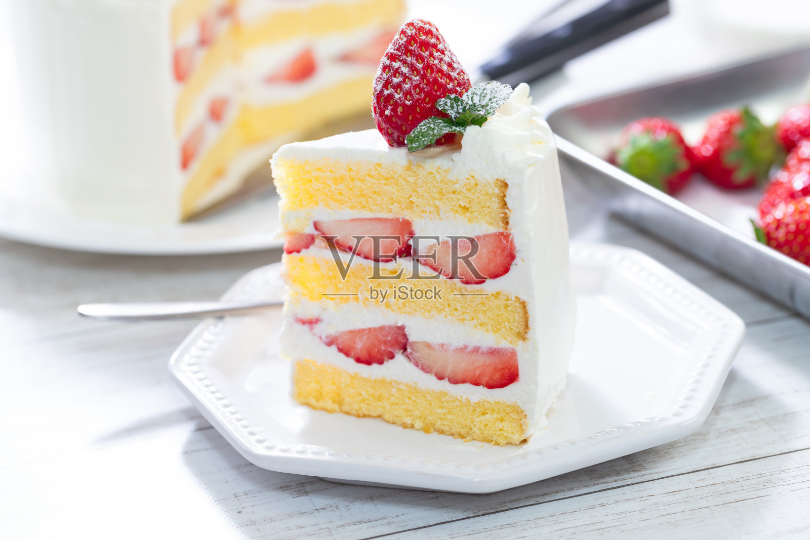 白色木桌上放着草莓奶油海绵蛋糕照片摄影图片