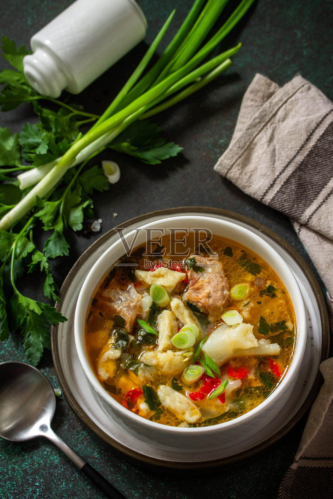 热腾腾的美味牛肉汤。黑色的石头背景上自制的肉、蔬菜和汤圆。照片摄影图片