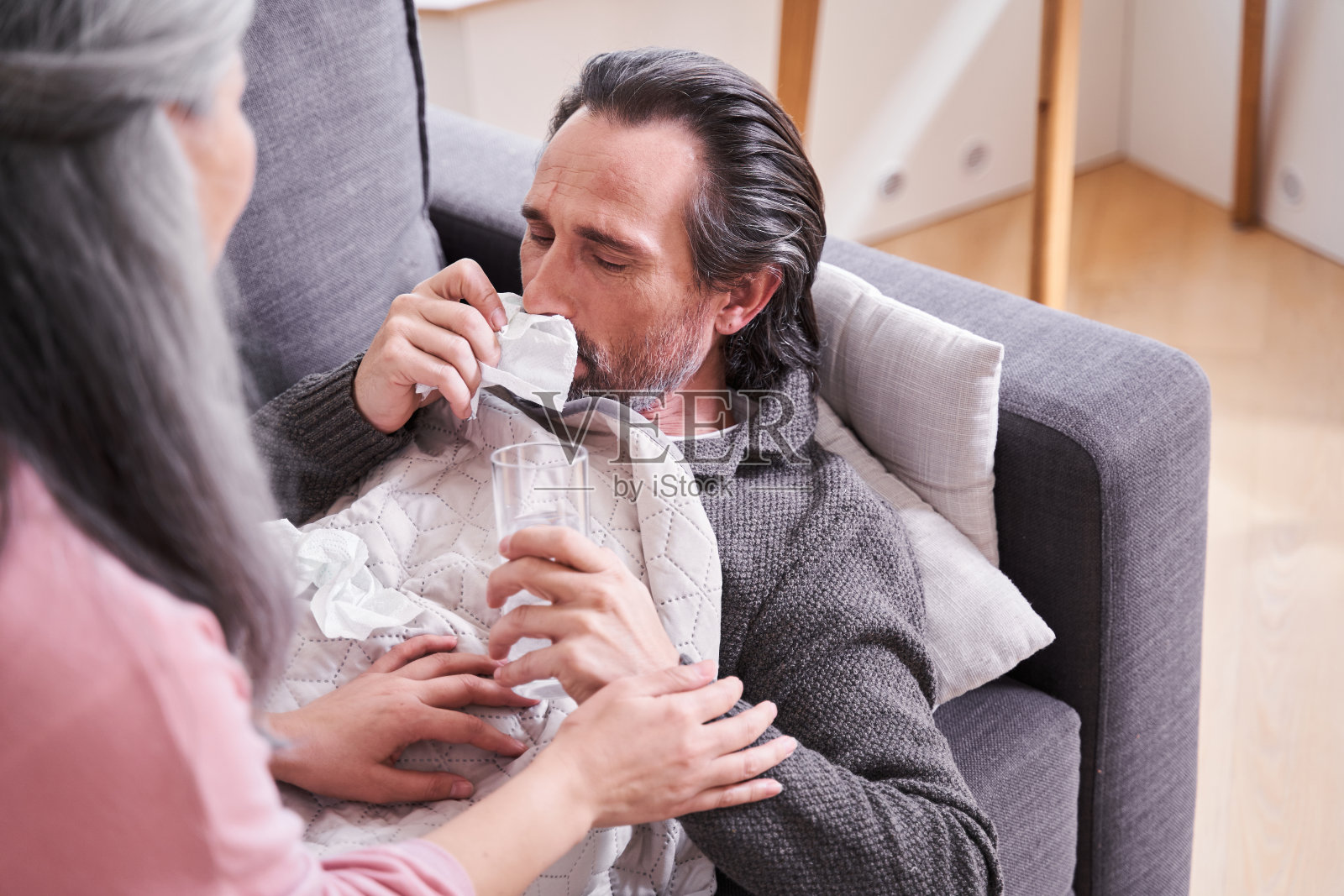 坐在她生病的老丈夫旁边的女人照片摄影图片