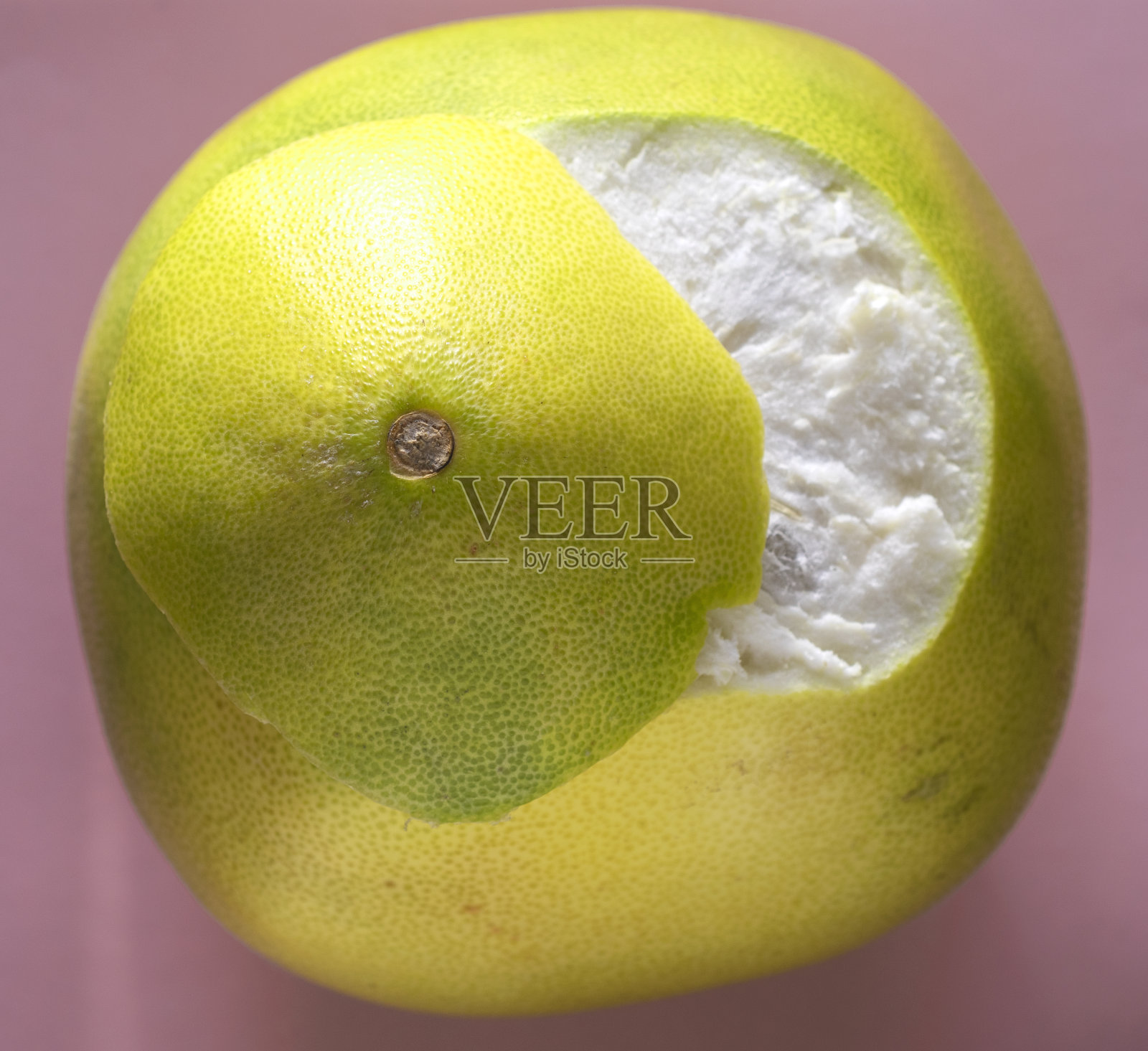 从上面半剥皮的柚子在粉红色的背景上看照片摄影图片