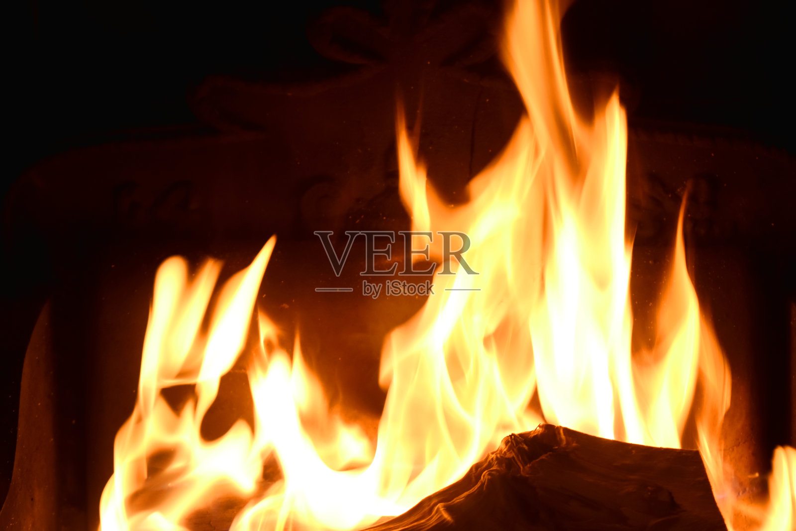 在壁炉中燃烧的原木的跳舞火焰的特写镜头,在圣诞节假期中温暖的灯光照片摄影图片