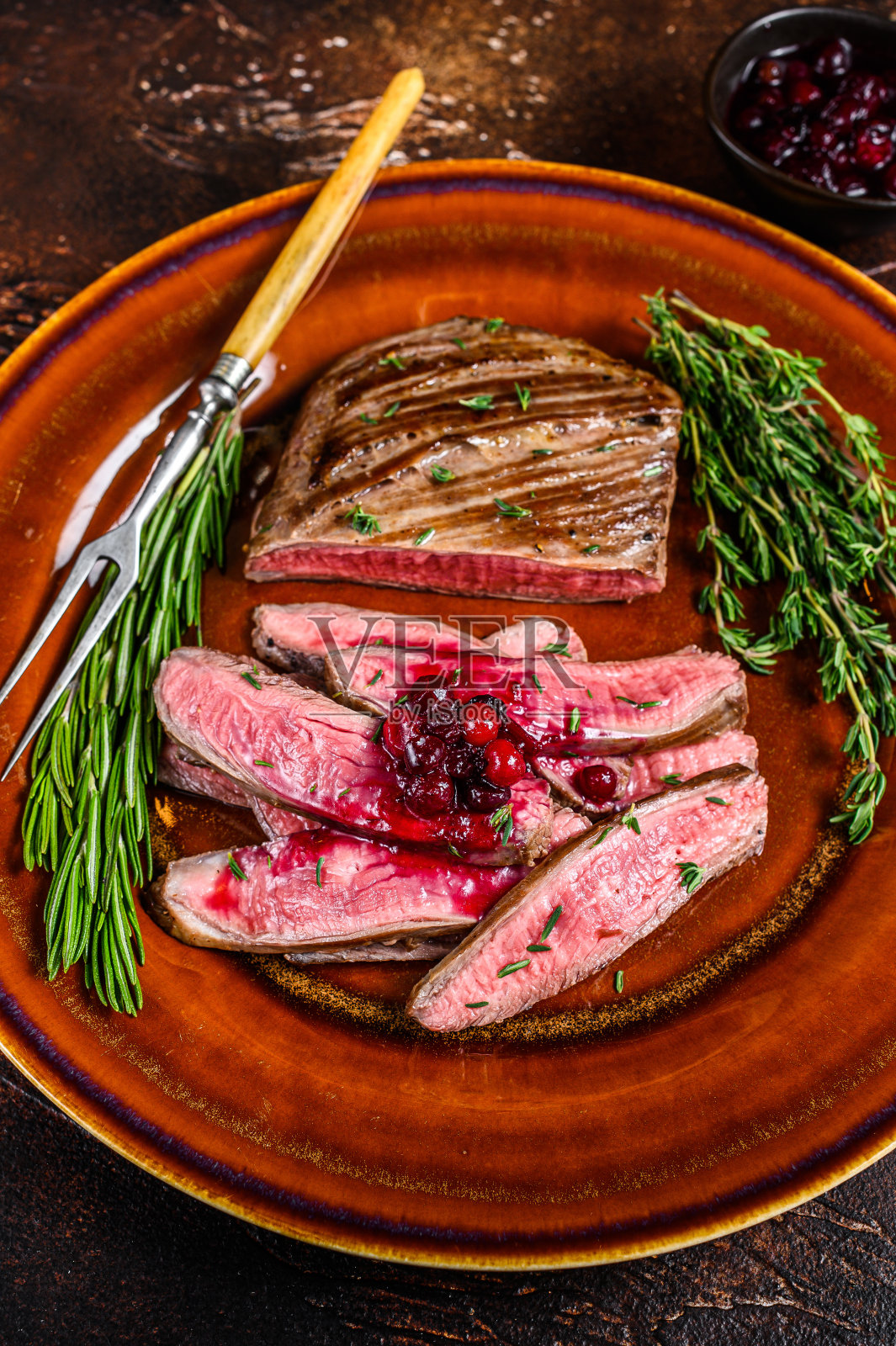 在盘子上煎的切成薄片的牛腩肉或扁牛肉。黑暗的背景。俯视图照片摄影图片