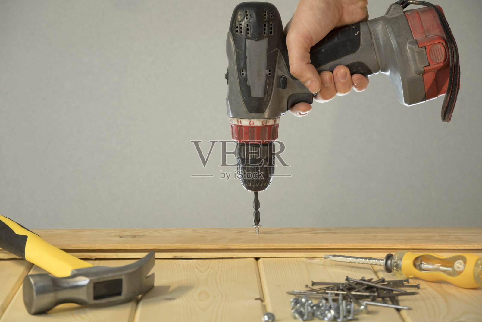 用螺丝刀把螺丝拧进去。施工工具。做房屋维修。做你自己。用螺丝刀把钢钉进木板里。工具的概念和修理工作。照片摄影图片