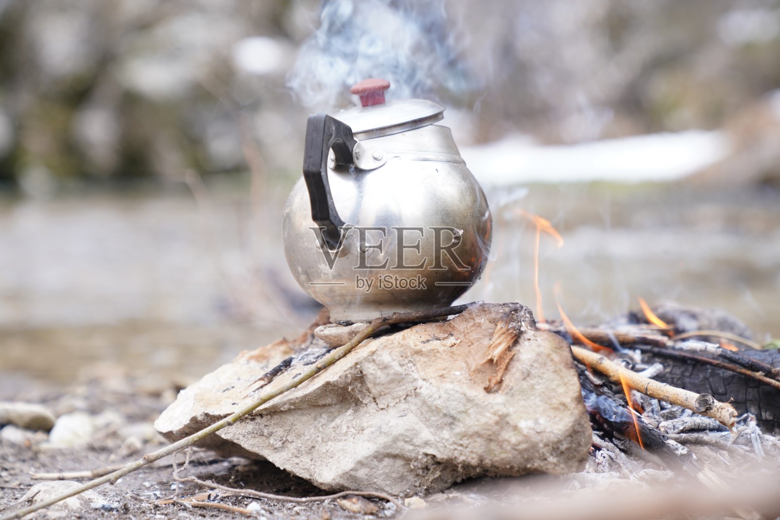 冒热气的水壶在燃烧的原木柴火营火。近距离照片摄影图片