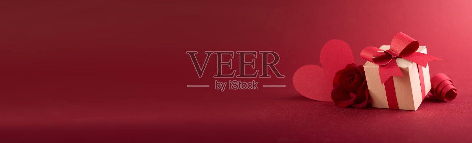 纸艺情人节礼品盒banner:纸质彩带、蝴蝶结和爱心,红色背景留白照片摄影图片