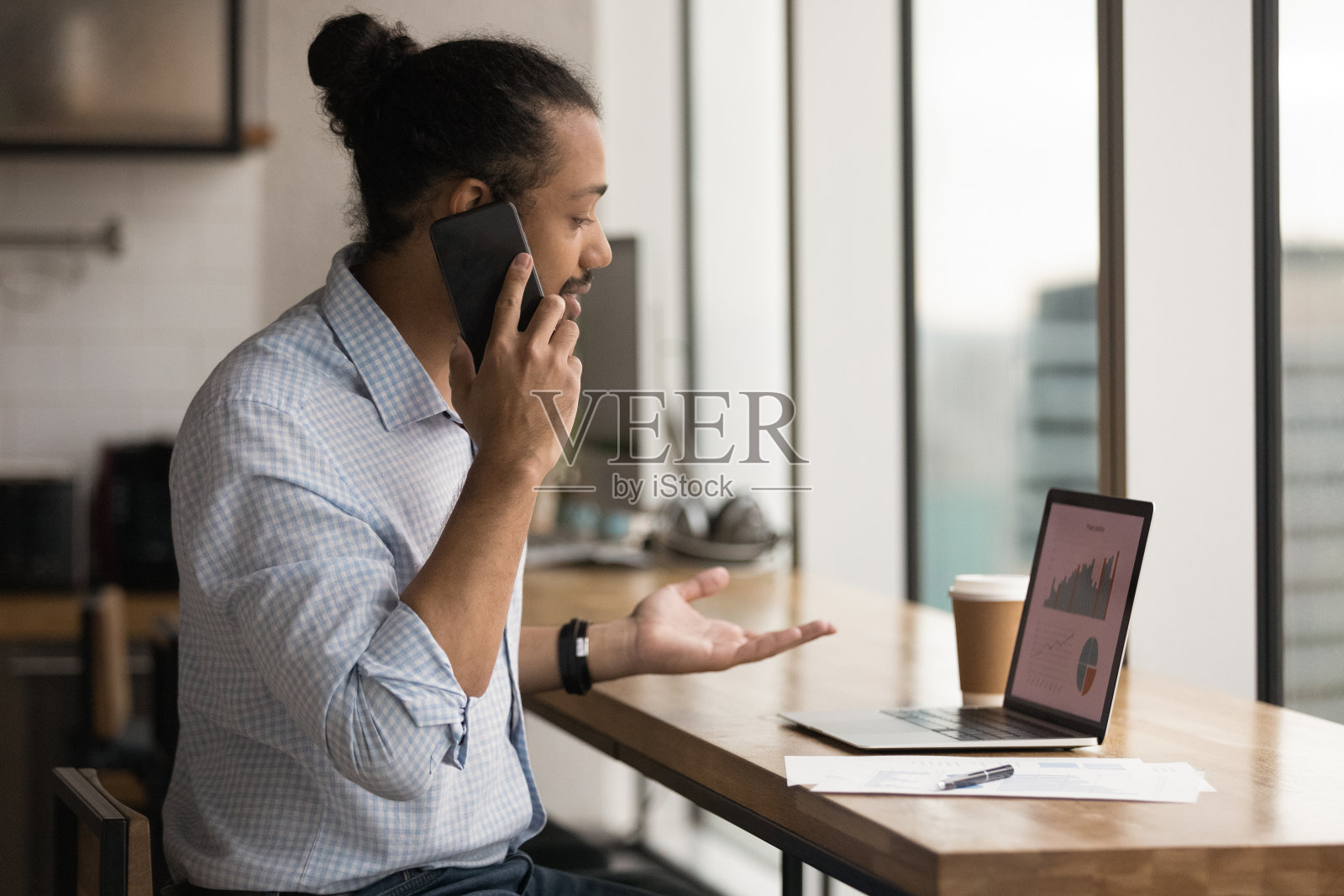 混血儿商人用电脑工作,用手机聊天照片摄影图片