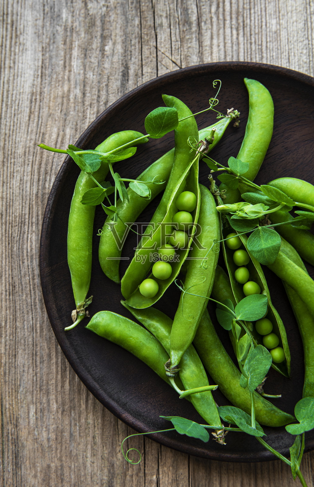 旧木背景上的盘子里的绿豌豆。从以上观点。照片摄影图片