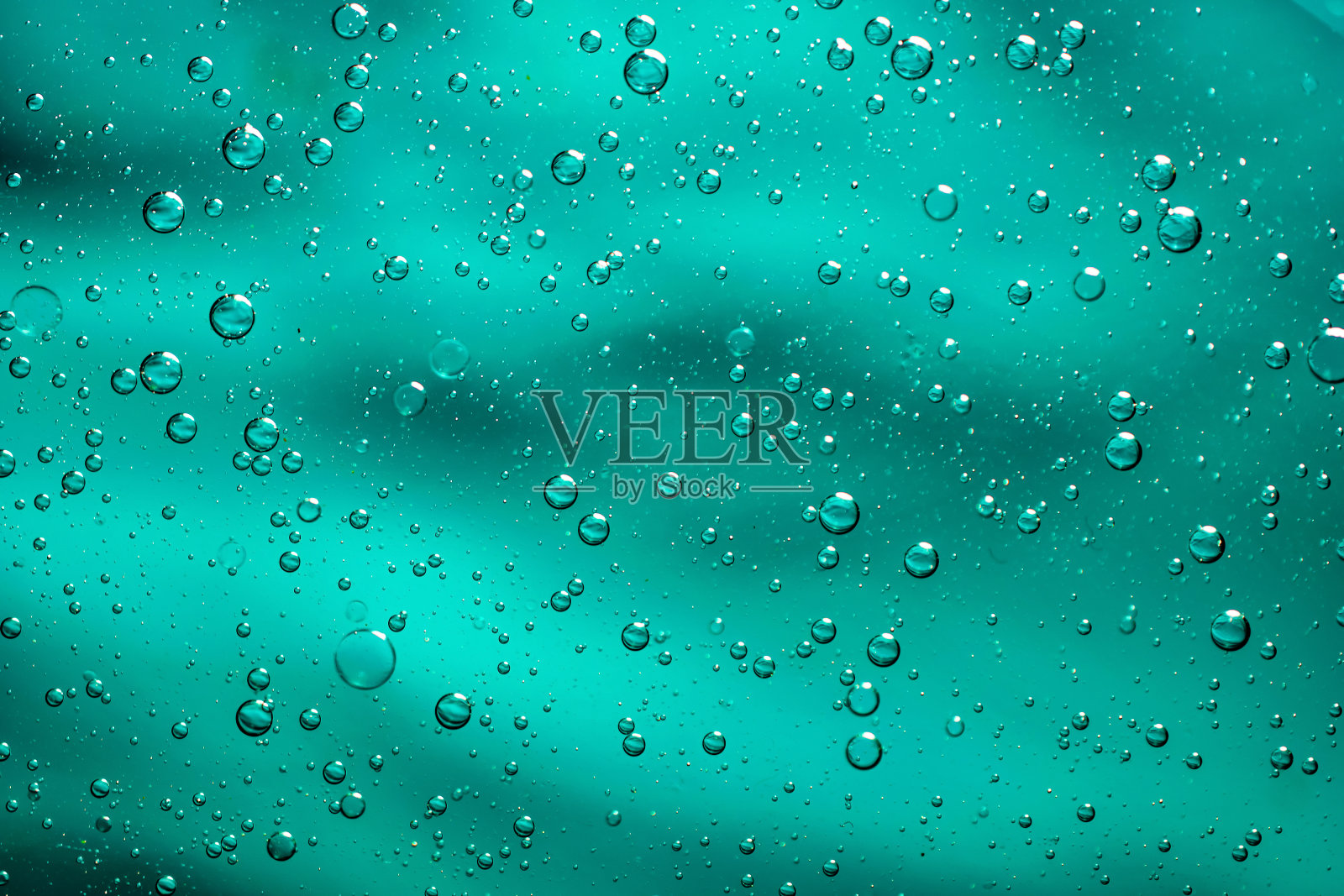 在蓝色背景上,油滴在水上照片摄影图片