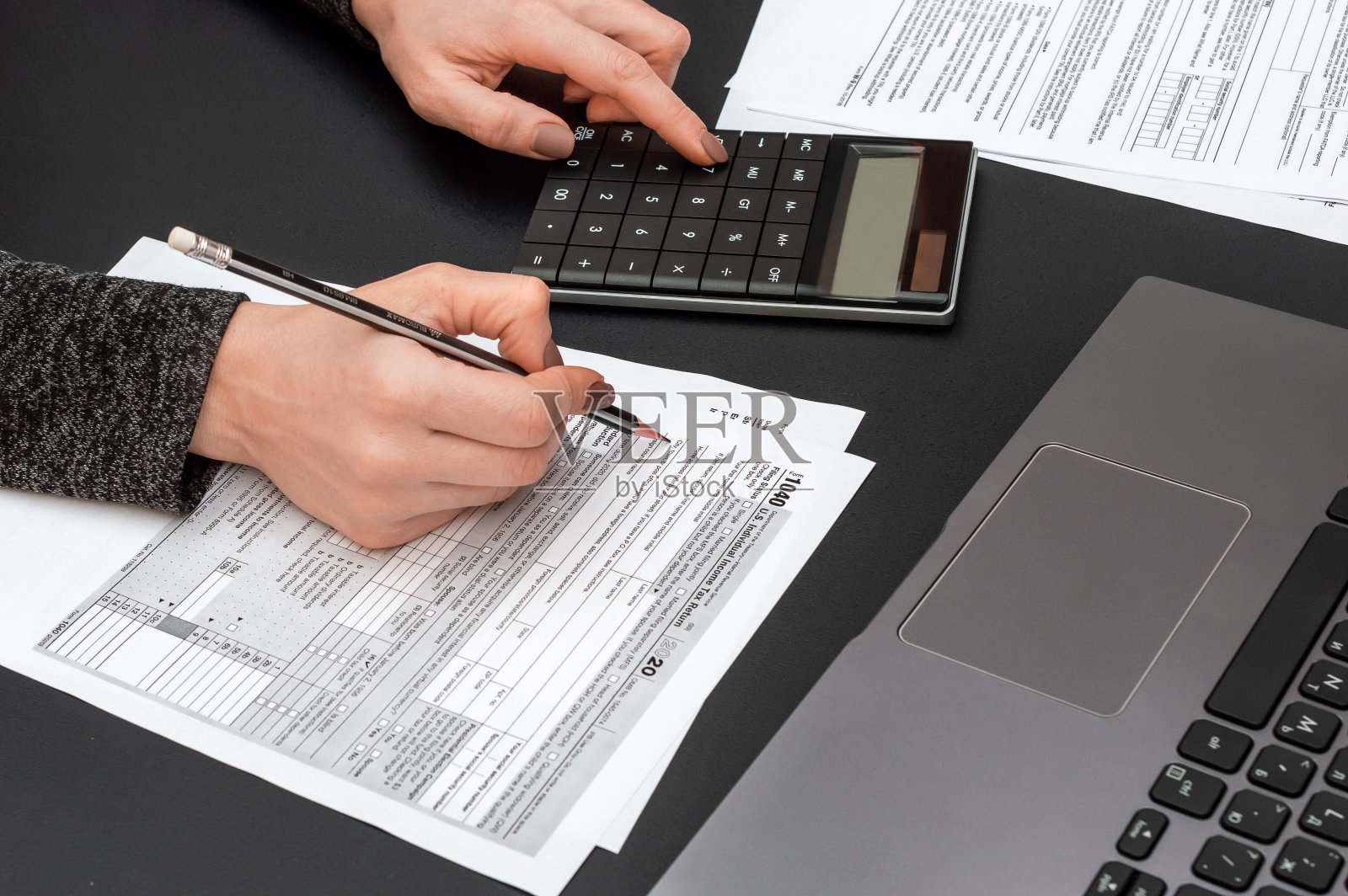 妇女填写税务表格在办公室工作。照片摄影图片