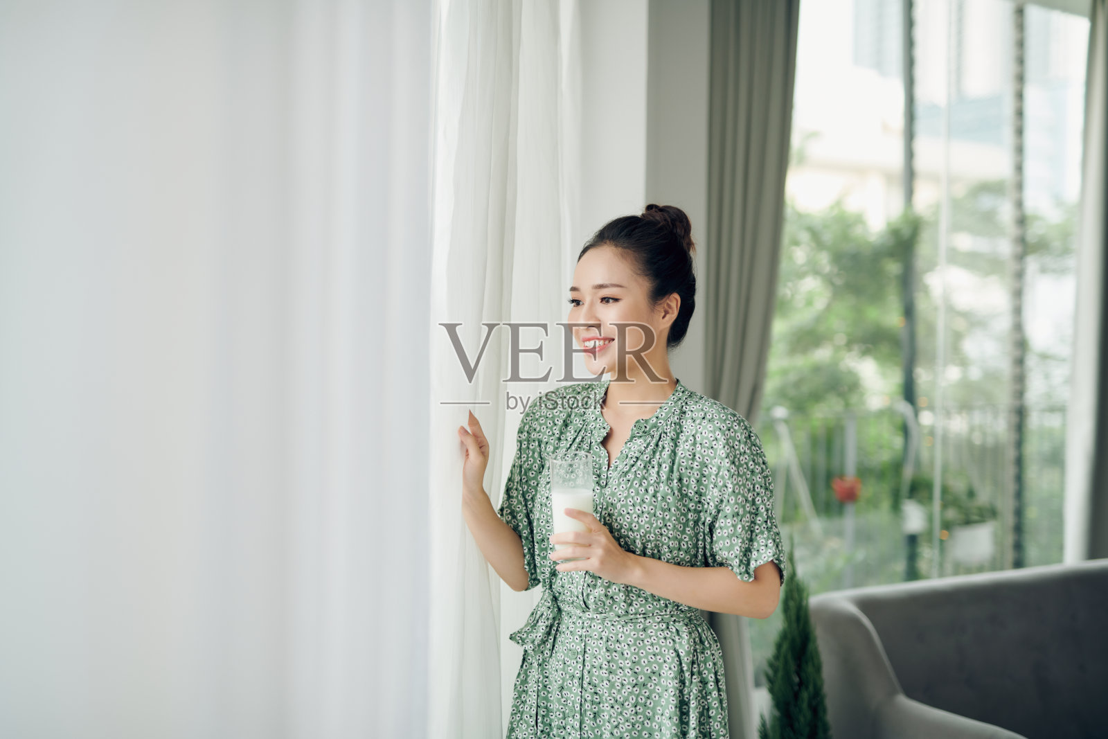 亚洲美女朋友们站着,捧着一杯牛奶,在早晨关上窗户和窗帘与拷贝空间。照片摄影图片