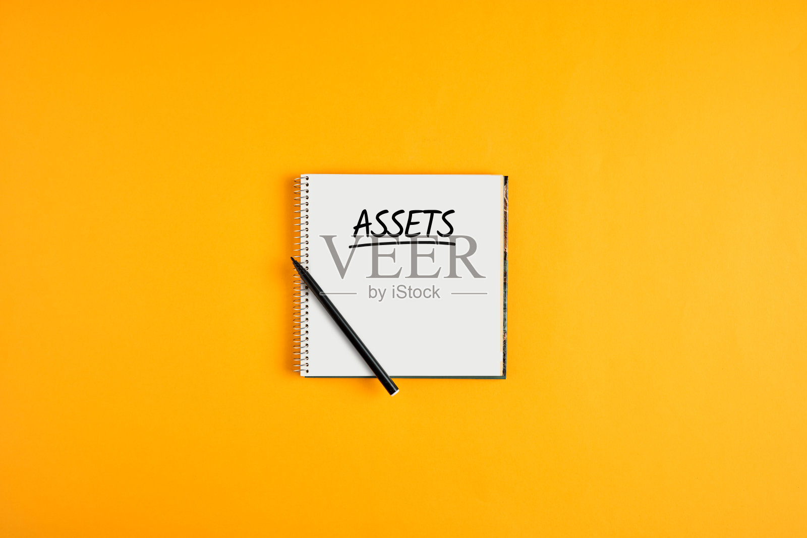 文字资产写在笔记本上,用钢笔在黄色的背景和复制空间。库存资产管理照片摄影图片