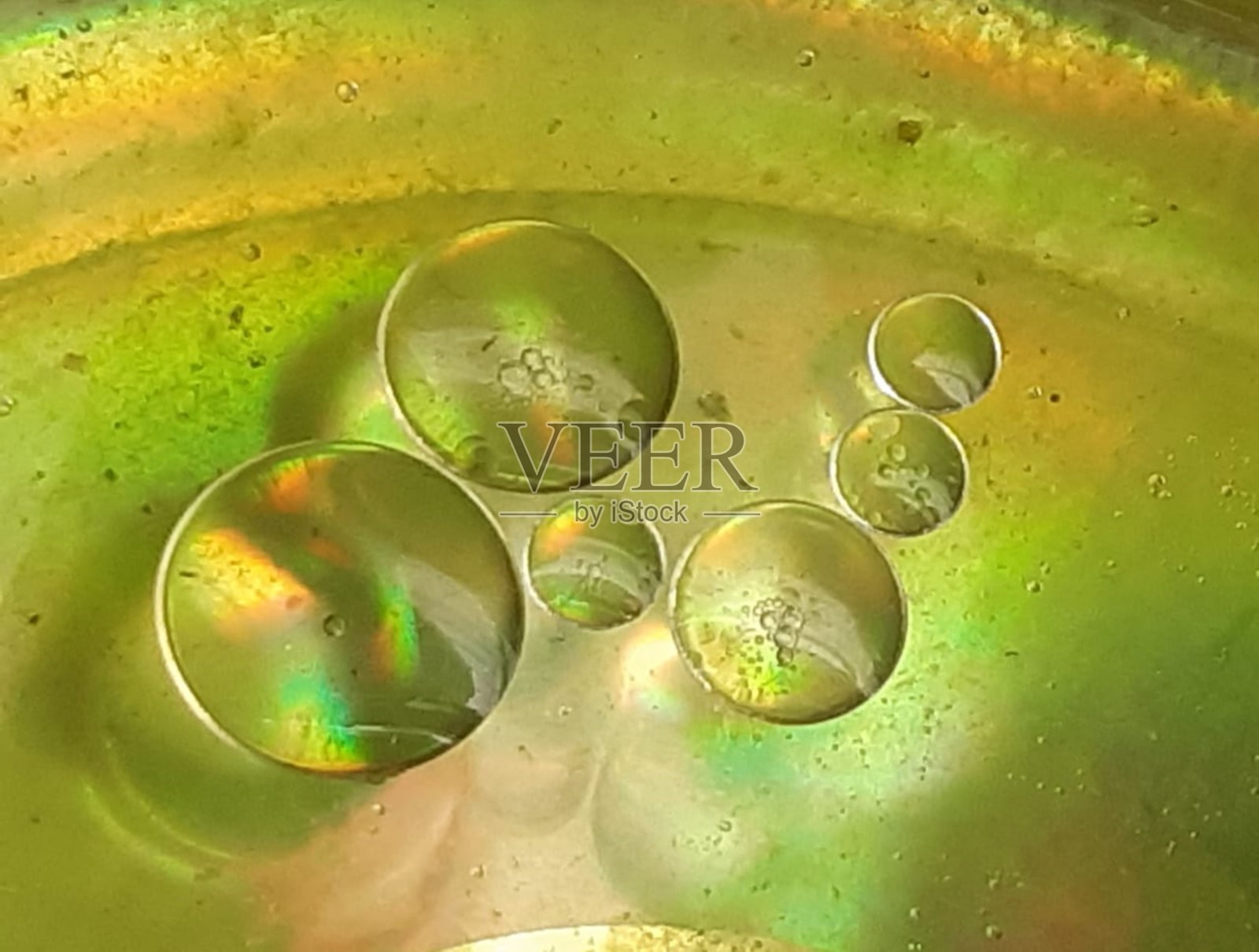 在绿色背景上漂浮在液体中的油球的抽象描绘照片摄影图片