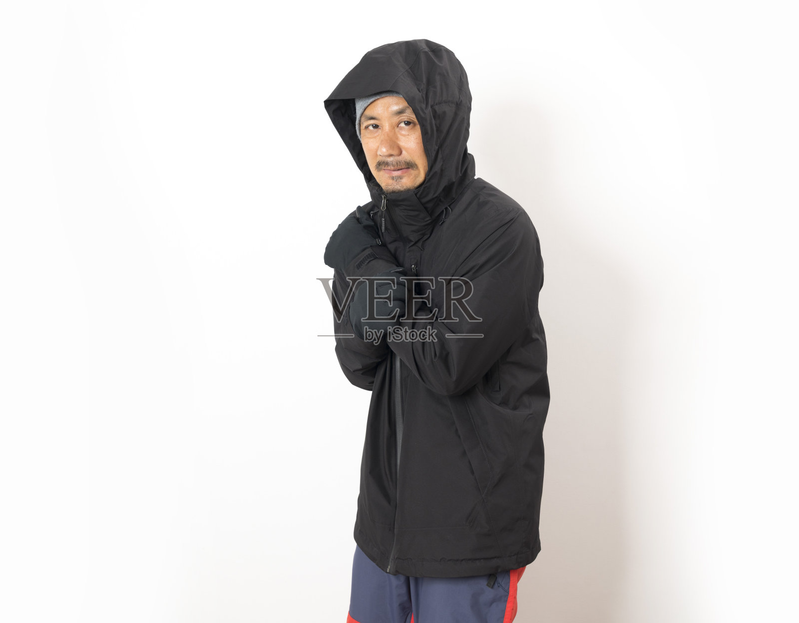 中年亚洲男子,穿黑色冬季夹克,戴手套和帽子。照片摄影图片