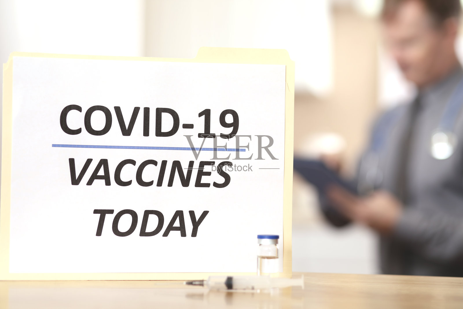 COVID-19:医生准备接种疫苗。标志,注射器,小瓶前景。照片摄影图片