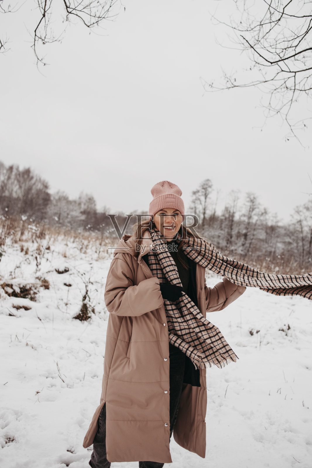 年轻的黑发女人穿着大衣或羽绒服,戴着围巾在户外过冬照片摄影图片