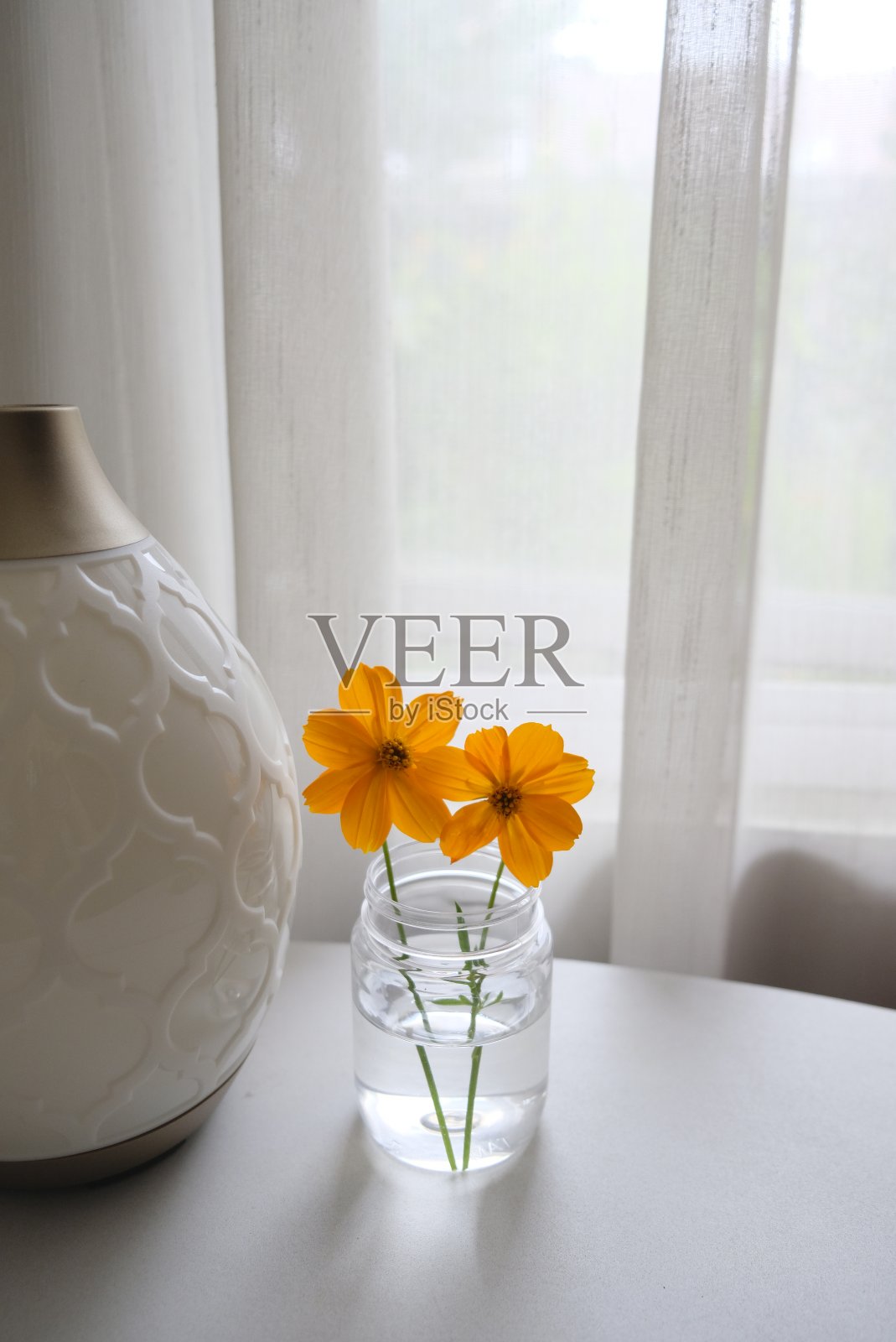 靠近窗户的桌子上有橙色的花。照片摄影图片