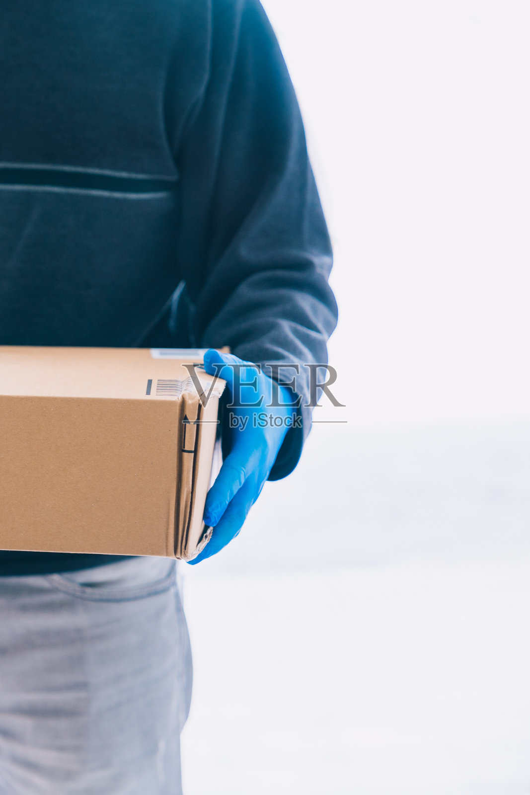 快递员递送一个装有蓝色乳胶手套的包裹,作为预防冠状病毒的措施。照片摄影图片
