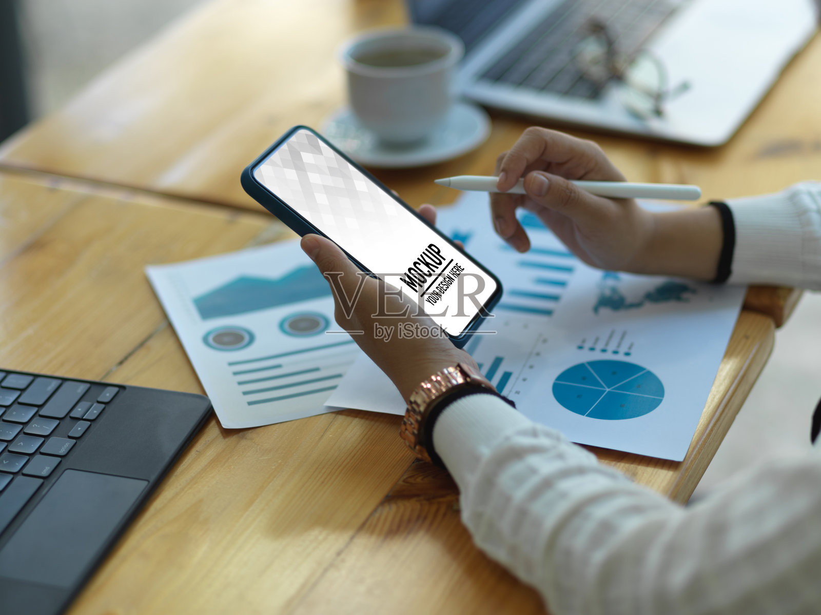 女商人一边用智能手机一边在木桌上处理文书工作照片摄影图片