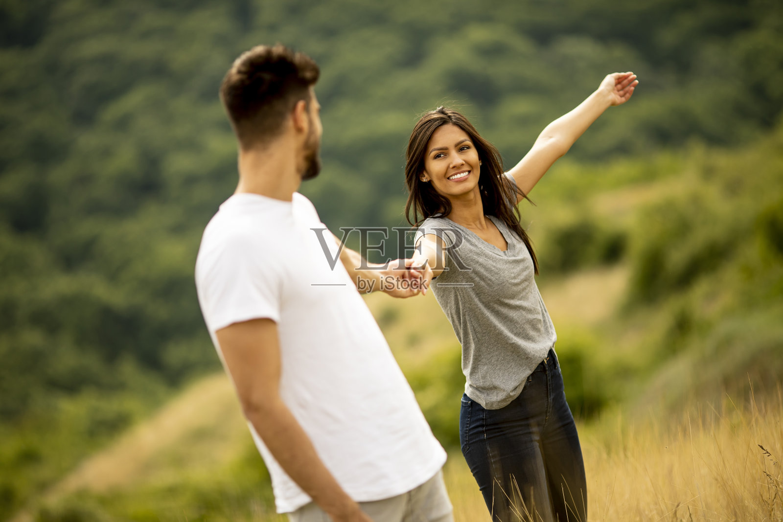 快乐的年轻情侣在草地上散步照片摄影图片