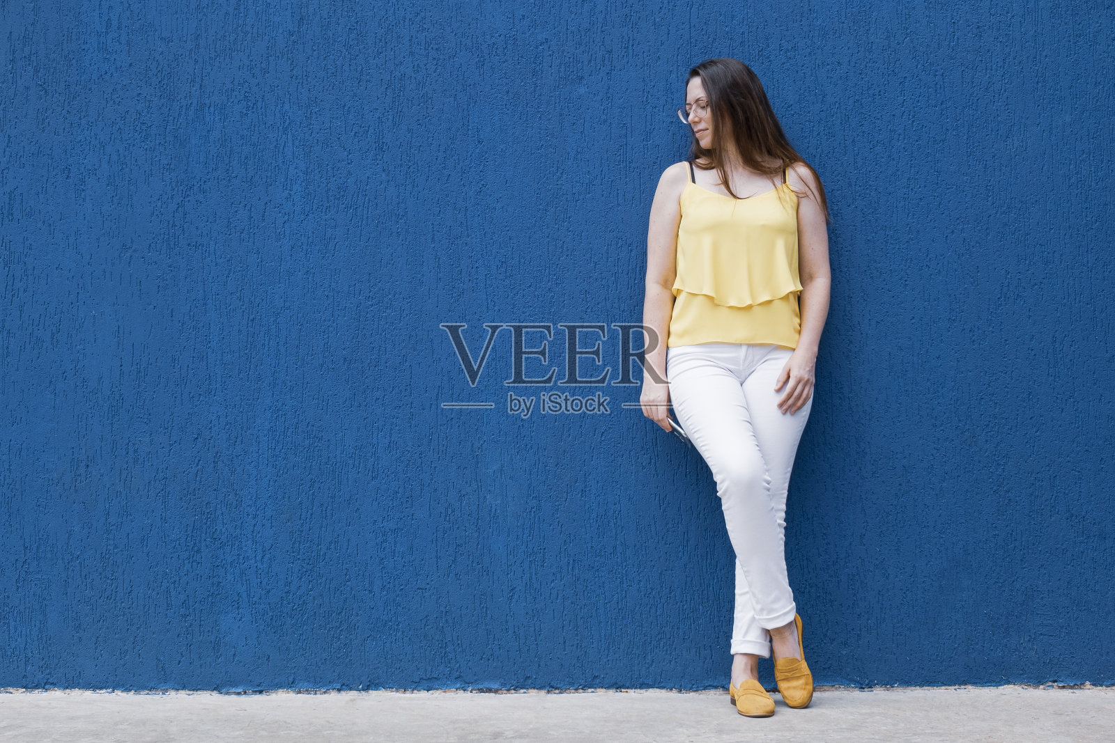 一个美丽的女人的肖像站在墙的蓝色照片摄影图片