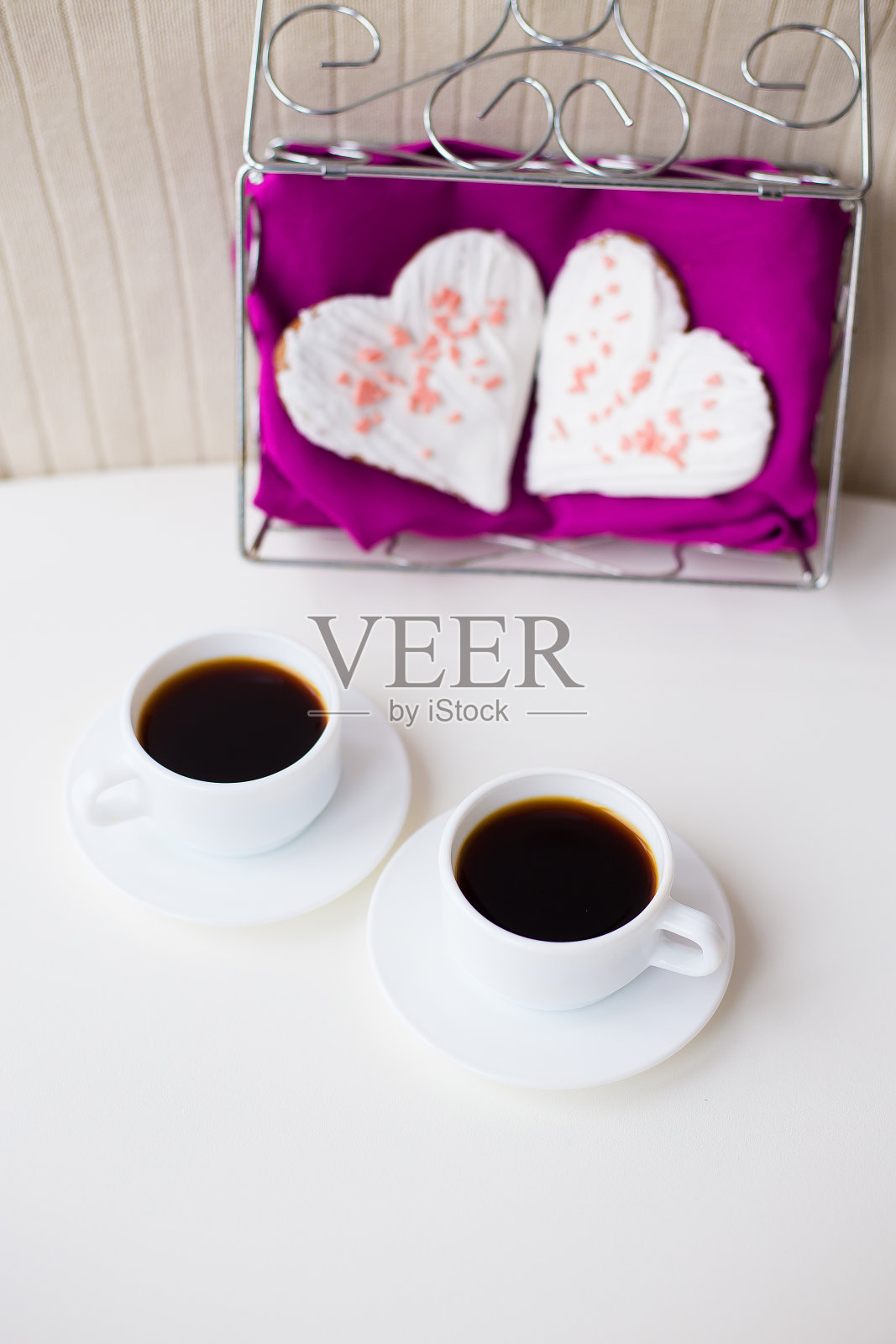 两杯咖啡和粉红色餐巾上的心形饼干照片摄影图片