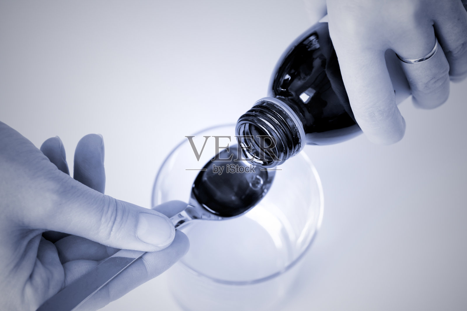 靠近女性的手把咳嗽和呕吐糖浆倒进勺子里照片摄影图片