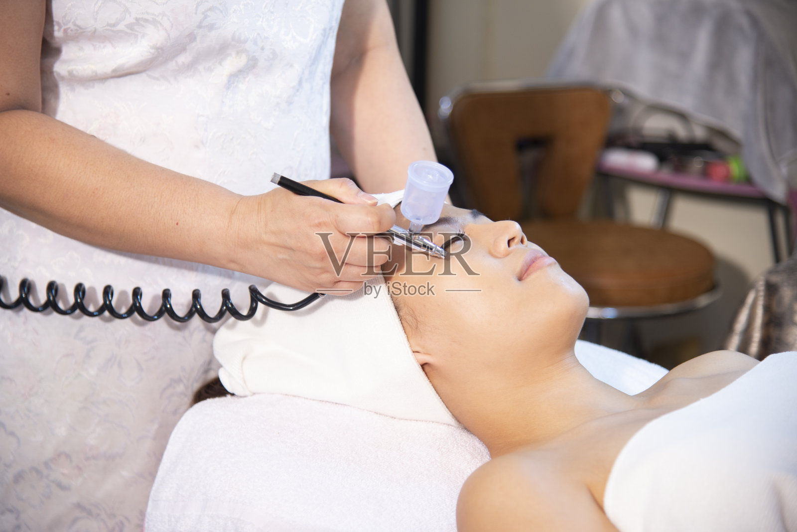 年轻美丽的亚洲女人获得提升,抗衰老,脸部按摩和皮肤护理,通过电穿孔面部治疗美容美容。照片摄影图片